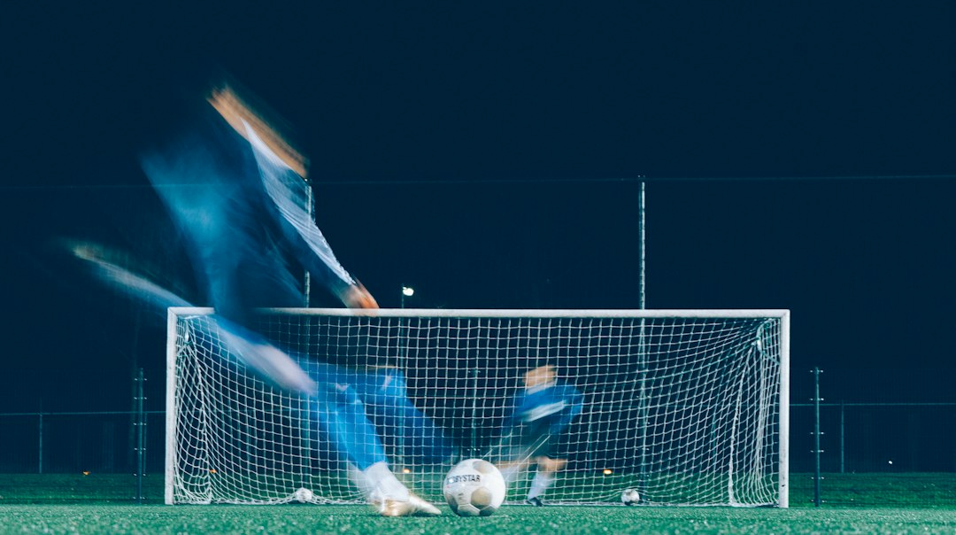 Fußballspieler schießt beim Training auf ein Tor; Langzeitbelichtung zeigt den Torwart
